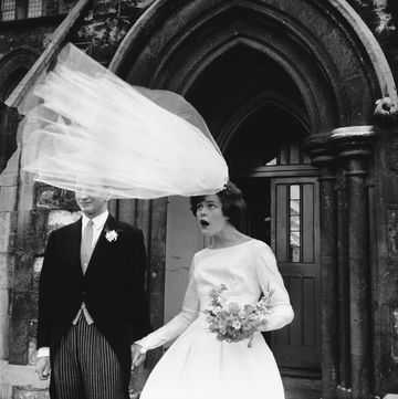 a gust of wind nearly lifts a eileen petticrews bridal veil from her head as she and her groom, robert greenhill, stand outside saint john de evangelist church in notting hill gate, london, england, uk photo by © hulton deutsch collectioncorbiscorbis via getty images